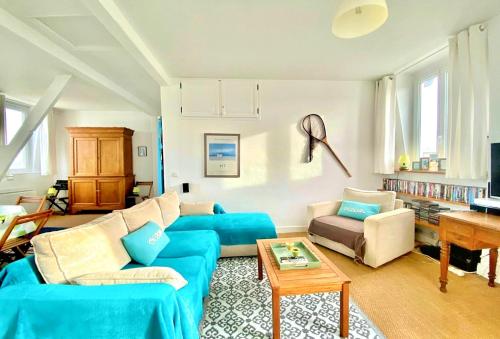 un salon avec un canapé bleu et une table dans l'établissement LESPARISNORMANDS - la terrasse Louvard, à Villers-sur-Mer