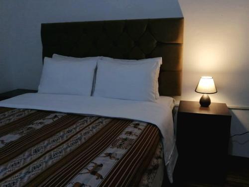 a bed in a room with a lamp on a table at Magnolia Andina in Cusco