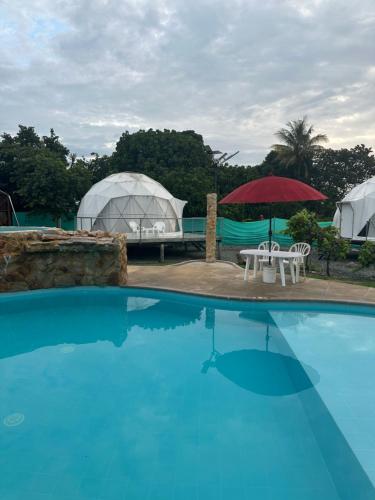 a swimming pool with a tent and a table and umbrella at Eco Cabañas Montana in Santa Helena