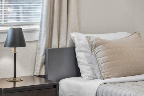 a bed with white pillows and a table with a lamp at Hot Tub, Fire Pit, Dog Friendly, Heart of Sisters, Amenities in Sisters
