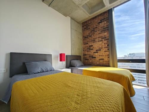 two beds in a room with a large window at Lux 2 BR apartment, swimming pool, gym and free parking spot in downtown Monterrey in Monterrey