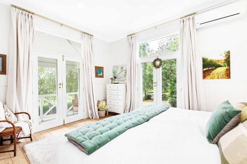 une chambre avec un grand lit blanc et de grandes fenêtres dans l'établissement SPRIGG COTTAGE Adelaide Hills Luxury Retreat, à Crafers