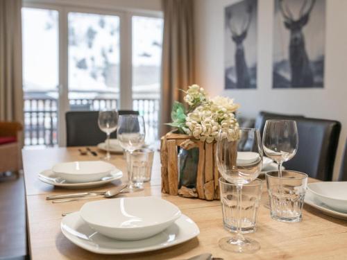 a wooden table with plates and wine glasses on it at Emma Top 2 in Dienten am Hochkönig