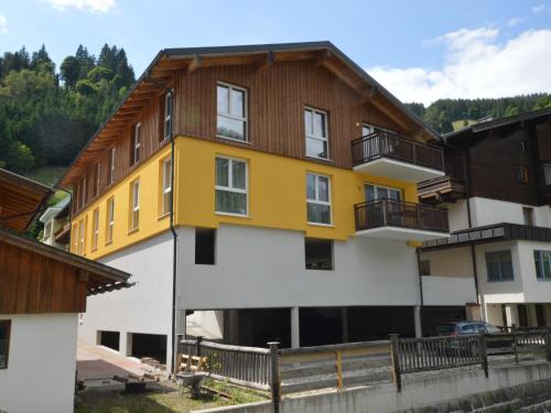 a yellow and white building with a wooden roof at Emma Top 2 in Dienten am Hochkönig