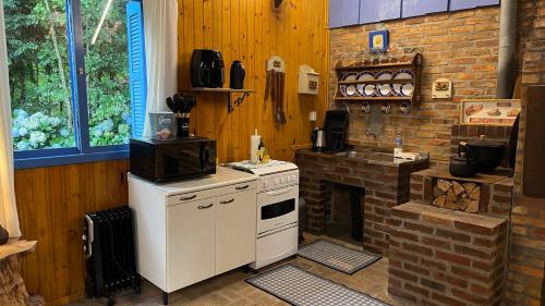 a kitchen with a stove and a brick wall at Charmoso Chalé Hortênsia em Gramado in Gramado