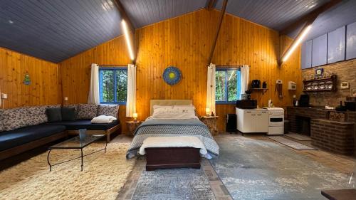 a bedroom with a bed and a couch in a room at Charmoso Chalé Hortênsia em Gramado in Gramado