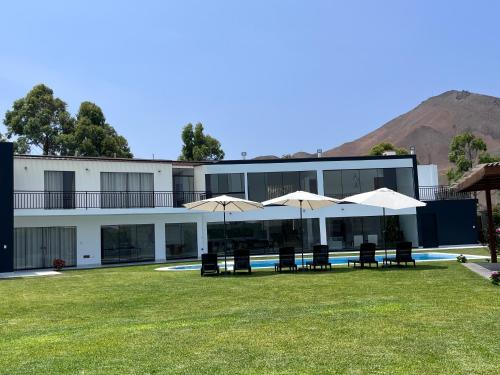 a building with a yard with chairs and umbrellas at Casa de Campo VIP San Andrés in San Andrés
