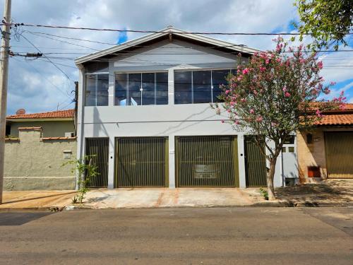 a white house with a tree in front of it at Casa perto do Parque dos Saltos - Brotas - Casa 3 in Brotas