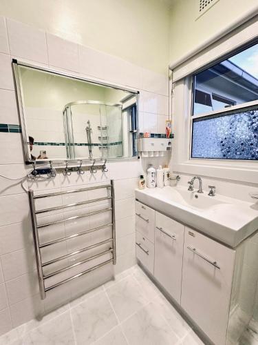 a white bathroom with a sink and a window at Rose Homey Home in Glenorchy