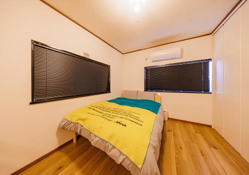 a bedroom with a bed with a yellow blanket at HirakataBase in Hirakata