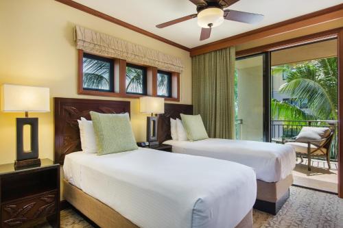 two beds in a hotel room with a balcony at Koloa Landing Resort at Po'ipu, Autograph Collection in Koloa