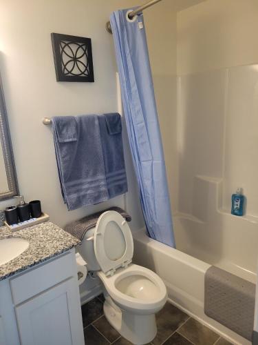 a bathroom with a toilet and a shower with blue towels at SC 3745 New Townhouse Ft Jackson & USC in Columbia