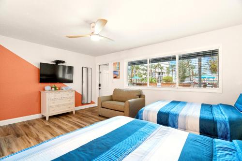 a bedroom with a bed and a tv and a chair at Boutique Beach Retreat in St Pete Beach