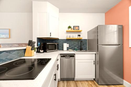 a kitchen with white cabinets and a stainless steel refrigerator at Boutique Beach Retreat in St Pete Beach
