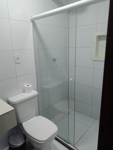 a bathroom with a toilet and a glass shower at Pousada Sol & Mar in Cayru