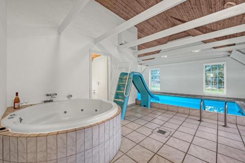 baño grande con bañera y tobogán en Renovated Thatched Pool House By The North Sea For 16 People, en Ulfborg