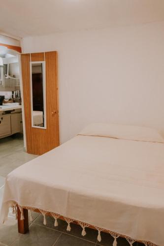 a white bed in a room with a kitchen at Departamento en Bahías de Huatulco in Santa Cruz Huatulco