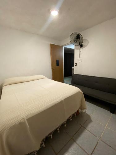 a bedroom with a white bed and a fan at Departamento en Bahías de Huatulco in Santa Cruz Huatulco