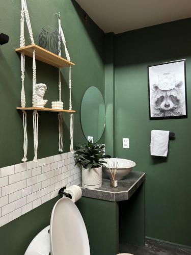 a green bathroom with a toilet and a sink at Encanto Taxqueño in Taxco de Alarcón