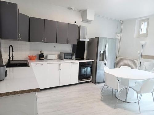 - une cuisine avec des placards blancs, une table et un réfrigérateur dans l'établissement maison spacieuse à coulommiers 8 couchages, à Coulommiers