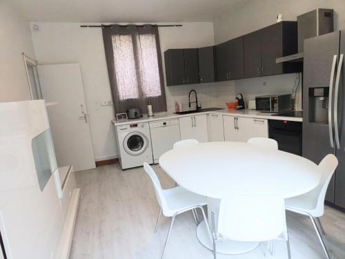 une cuisine avec une table blanche et un lave-linge dans l'établissement maison spacieuse à coulommiers 8 couchages, à Coulommiers
