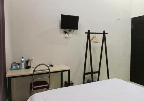 a bedroom with a bed and a desk and a tv at GRAND KHALIFAH Guesthouse in Sumbawa Besar