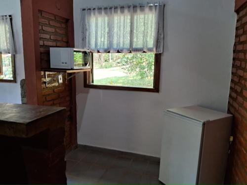 a kitchen with a window and a refrigerator at Sitio Serenar Chalés Equipados in Penedo