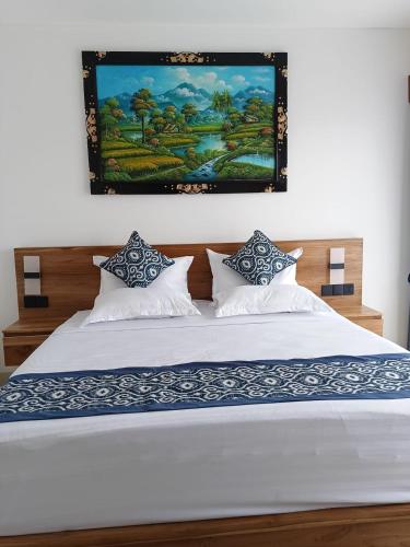 a bedroom with a white bed with a painting on the wall at Tulak House in Blahbatu