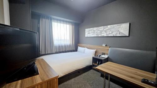 a hotel room with a bed and a flat screen tv at Hotel Route Inn Kounosu in Kōnosu