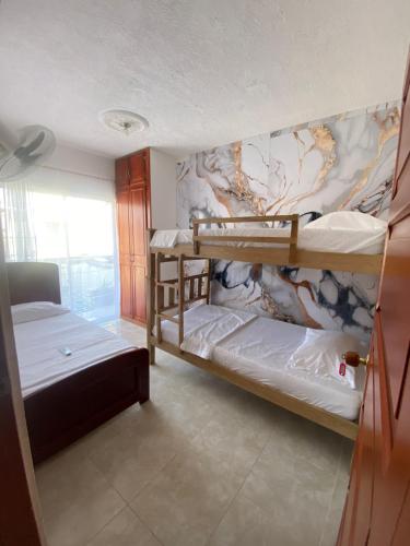 een kamer met 2 stapelbedden en een muur bij Hostal El Amanecer Costero in Santa Marta