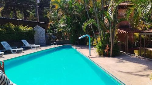 a swimming pool in a yard with palm trees at Aconchego Caminho das Cachoeiras in Rio Acima