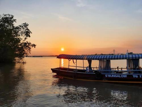 a boat on the water with the sunset in the background at Cồn Phụng Resort Mekong - Nature Escape with Free Boat Shuttle & Fishing in Ben Tre