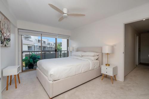 a white bedroom with a bed and a ceiling fan at Spacious 2-Bed Apartment Near Dining & Attractions in Kingston
