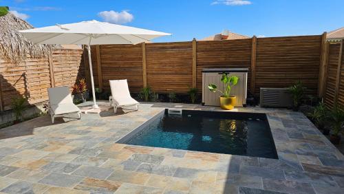 piscina con ombrellone e due sedie di La villa SunCloud a Le Diamant