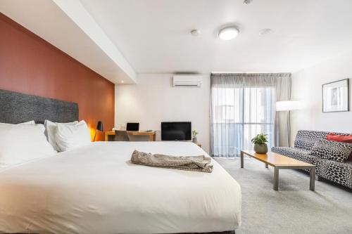 a bedroom with a large white bed and a chair at Punthill Apartment Hotel - Little Bourke in Melbourne