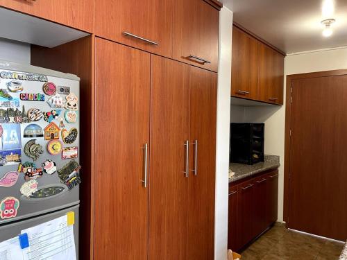 a kitchen with wooden cabinets and a refrigerator with magnets at Tu hogar lejos de tu casa in Atuntaqui