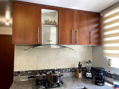 a kitchen with wooden cabinets and a stove top at Tu hogar lejos de tu casa in Atuntaqui