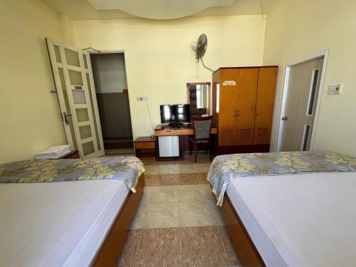 a room with two beds and a desk with a tv at Ho Phong Hotel in Phan Rang