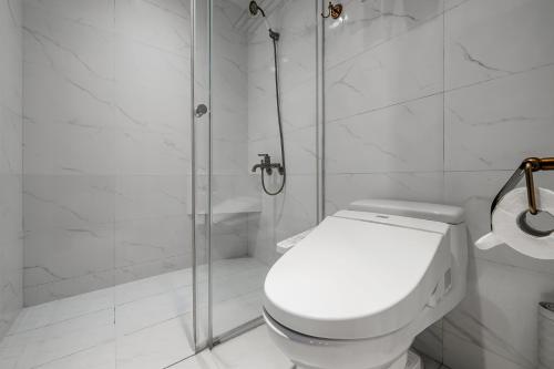 a white bathroom with a shower and a toilet at Dream Mansion Hotel in Taichung
