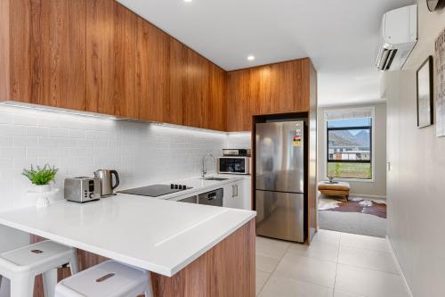 uma cozinha com um balcão branco e armários de madeira em New 4BRs Townhouse, Walk to Shops & Cafes, 5mins to Airport, 30mins to Ski em Queenstown