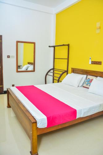 a bedroom with a large bed with a red and yellow wall at Ocean Bliss Villa Mirissa in Kamburugamuwa