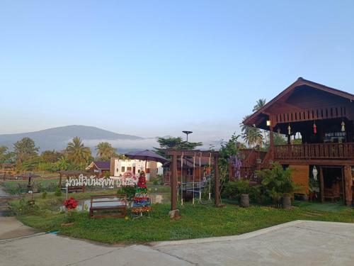 a park with a playground and a building at ม่วนใจ๋ปันสุข โฮมสเตย์แอนคาเฟ่ Muanjai punsuk homestay and cafe in Chom Thong