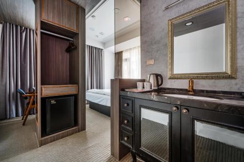 a bathroom with a sink and a mirror and a bed at Dream Mansion Hotel in Taichung