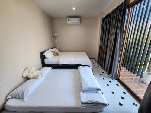 two beds in a room with a window at P2 Location pool villa in Ban Pak Chong