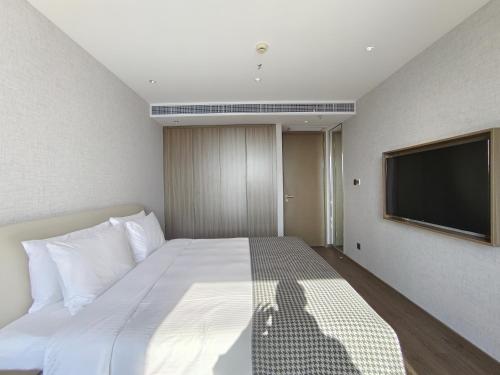 a bedroom with a bed and a flat screen tv at Somerset Xuhui Riverside Shanghai serviced apartments in Shanghai