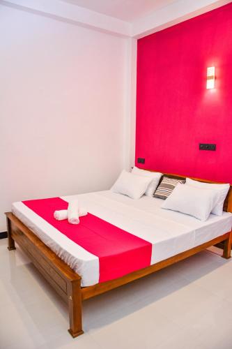 a bedroom with a large bed with a red wall at Ocean Bliss Villa Mirissa in Kamburugamuwa