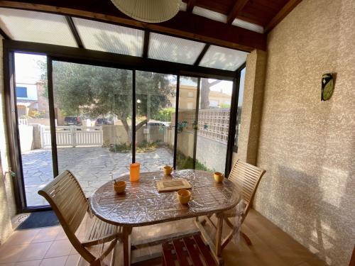 une table et des chaises dans une pièce avec une grande fenêtre dans l'établissement Villa T3 mezzanine, climatisée avec garage, 6 personnes, proche de la mer - FR-1-795-32, à Fleury