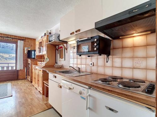 une cuisine avec un évier et une cuisinière four supérieur dans l'établissement Studio cosy à La Clusaz avec balcon et garage, animaux admis - FR-1-818-9, à La Clusaz