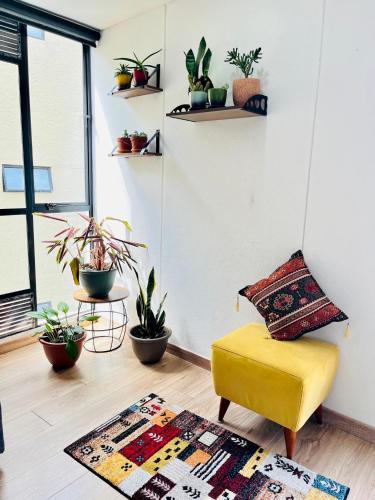 a living room with a yellow chair and plants at Comfy loft in La Candelaria in Bogotá