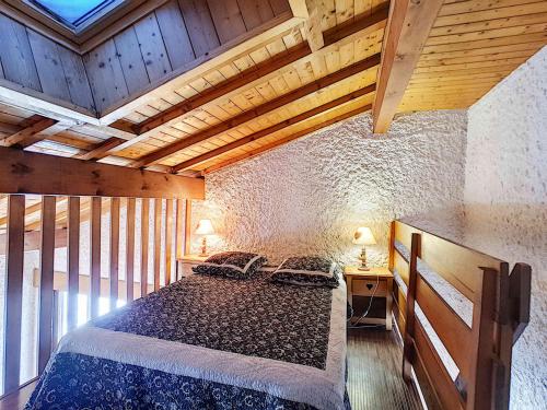 une chambre avec un grand lit dans une pièce avec des plafonds en bois dans l'établissement Duplex cosy à La Clusaz pour 5 pers, animaux admis - FR-1-818-61, à La Clusaz